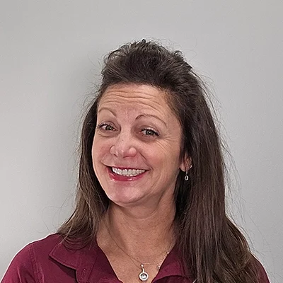 Nikki smiling in front of a grey wall.