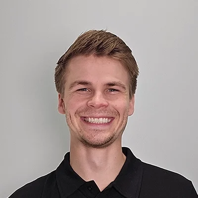 Seth smiling in front of a grey wall.